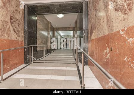 Grand marble entrance hallway with a ramp, stainless steel handrails, and a staircase visible in the distance. Stock Photo