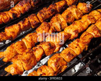 Grilling marinated chicken skewers over hot coals for barbecue Stock Photo