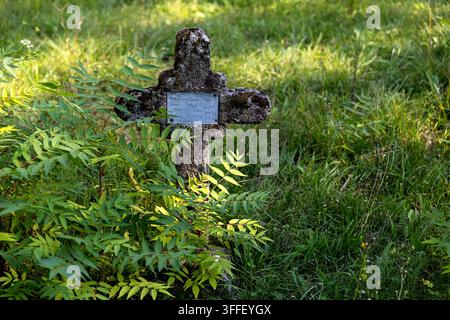 Historic Austro-Hungarian military cemetery with weathered stone grave markers of World War I soldiers among autumn trees in Brje pri Komnu. Stock Photo
