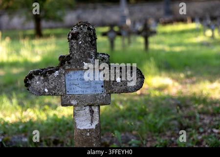 Historic Austro-Hungarian military cemetery with weathered stone grave markers of World War I soldiers among autumn trees in Brje pri Komnu. Stock Photo