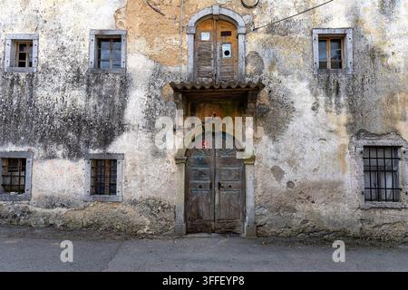 A beautiful close-up of a weathered historic wooden door on a traditional rustic stone karst house, showcasing authentic architectural details. Stock Photo