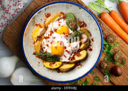 Spanish tapa of eggs with ham, Padrón peppers, and potatoes. Top-down view of the table. Stock Photo