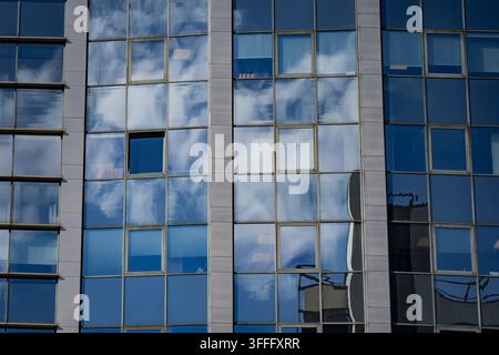 Glazed building facade with repeated window units, opening panes and vertical cladding strips, representing commercial architecture and building envel Stock Photo