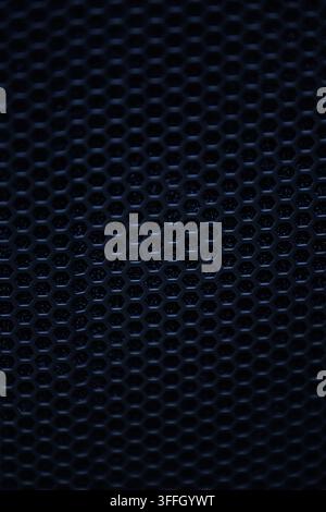A close-up macro photograph of a dark black metallic honeycomb grid with a shallow depth of field and soft bokeh, creating an abstract, moody, and tec Stock Photo
