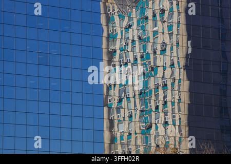 A detailed photograph capturing an abstract and distorted reflection of an older, multi-story residential building, with visible air conditioning unit Stock Photo