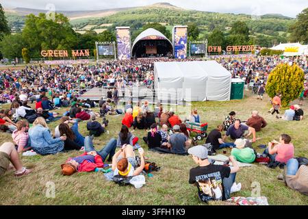 EXPANSIVE VIEW OF THE CROWD AT GREEN MAN FESTIVAL, REPORTAGE, GREEN MAN FESTIVAL 2014, BRECON, WALES, UK, 2014: A very large crowd of festival-goers is seen from a high vantage point, sitting and lying on the grass watching a performance on the main stage set against rolling green hills. Photo: Rob Watkins. INFO: The Green Man Festival is held annually in the Brecon Beacons in August. It celebrates alternative music, arts, literature, science and family-friendly culture in a beautiful mountain setting. The 2014 event was hot and sunny. Stock Photo