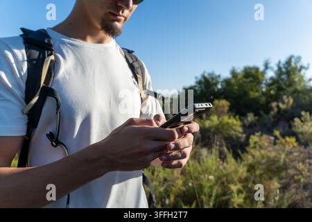 Man using smartphone for navigation during hiking Stock Photo