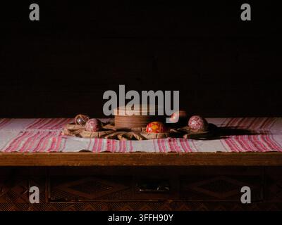 Traditional Ukrainian Easter eggs pysanky and carved wooden box on embroidered table runner in rustic setting Stock Photo
