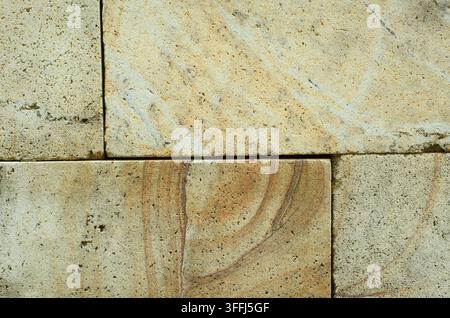 Close-up of natural stone wall blocks with rough porous texture and beige-gray tones. Shows detailed grain, natural pitting, and horizontal layering. Stock Photo