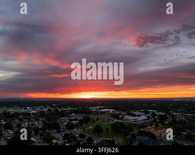 Evening sky ablaze with crimson and violet hues over peaceful residential area Stock Photo