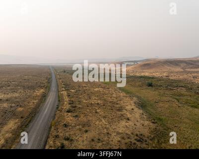 Long gravel path winds through arid plains with muted earth tones Stock Photo