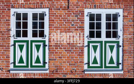 Close-up architectural view of two symmetrical windows with traditional green-and-white wooden shutters in Potsdam’s Dutch Quarter. Stock Photo