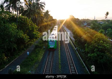 An Indonesian commuter train (Kereta Bandara YIA) utilizing a KAI Diesel-Electric Multiple Unit (KRDE) traveling near Patukan Station, Yogyakarta Stock Photo