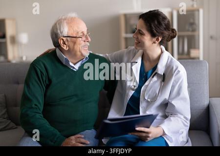 Senior man consulting with female doctor at home visit Stock Photo