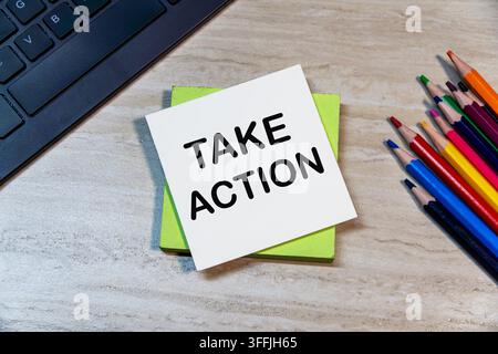 Take Action text on sticky note placed on keyboard background with colorful pencils on wooden office desk. Motivation and business concept. Stock Photo
