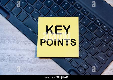 Key points written on yellow sticky note placed on laptop keyboard on wooden office desk background. Concept for summary. Stock Photo