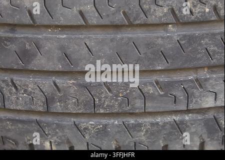 Close up of a used car tire showing detailed tread patterns, worn rubber surface, dirt, and textured grooves, highlighting the condition and structure Stock Photo