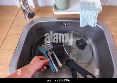 Close-up of a woman’s hands washing dishes in a kitchen, representing everyday household chores and cleaning. Stock Photo