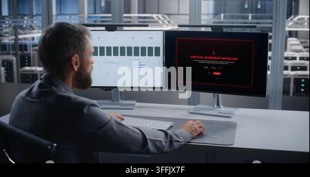 IT Specialist Monitors Server Infrastructure Across Dual Screens After Critical Overheating Alert, Troubleshooting Data Center Systems to Prevent Equipment Damage, Downtime, and Service Disruption. Stock Photo