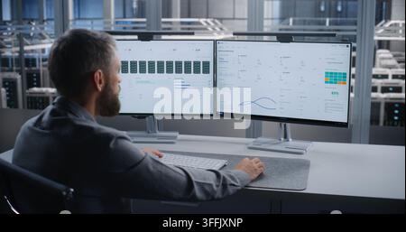 IT Specialist Monitors Server Infrastructure Across Dual Screens After Critical Overheating Alert, Troubleshooting Data Center Systems to Prevent Equipment Damage, Downtime, and Service Disruption. Stock Photo