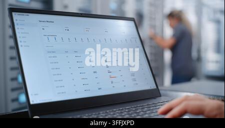 Male Network Engineer Monitors Server Telemetry as Critical Overheating Warning Appears, Analyzing System Metrics and Network Traffic While Responding to Infrastructure Performance Incident. Stock Photo