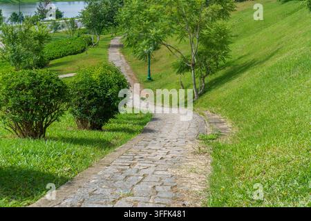Stone pathway winding through lush green park. Stock Photo