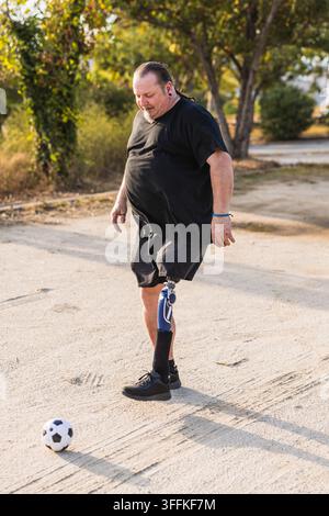 Man with prosthetic leg playing soccer outdoors Stock Photo