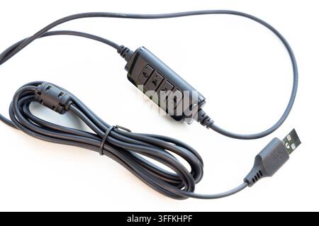 A black USB audio cable with inline controls rests on a white surface Stock Photo