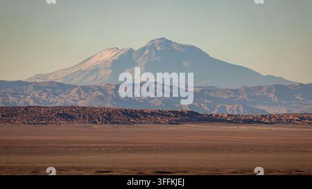 View of the vast arid landscape of the Atacama desert with rugged mountain ranges under a clear sky in Chile. Stock Photo