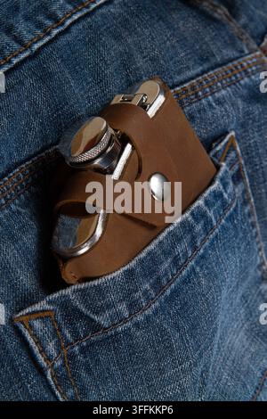 Hip flask in full grain leather case in jeans pocket Stock Photo