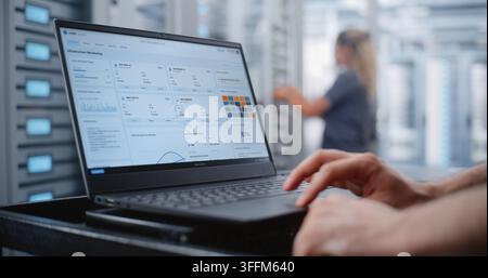 Male Data Center Engineer Responds to Critical Overheating Alert Through Linux CLI, Monitoring Server Health and Entering Emergency Commands While Sur Stock Photo