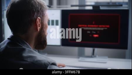 Data Center Technician Monitors Server Systems After Critical Overheating Alert, Analyzing Systems on Dual Screens to Resolve Issues, Protect Hardware Stock Photo