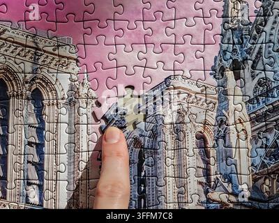 Hand inserting final missing piece into cathedral architectural jigsaw puzzle Stock Photo