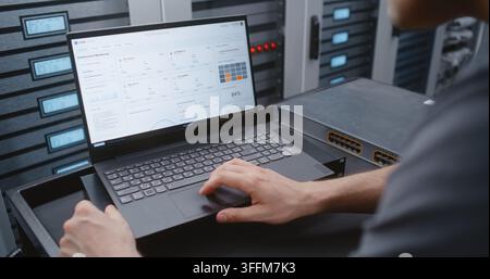 Male IT Engineer Handles DDoS Alert Using Linux Command Line, Reviewing Network Conditions and Performing Emergency Troubleshooting While Monitoring C Stock Photo