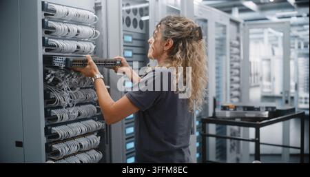 Female Engineer Mounts Replacement Network Switch in Modern Data Center Rack, Performing Hardware Upgrade and Infrastructure Maintenance to Improve Ne Stock Photo