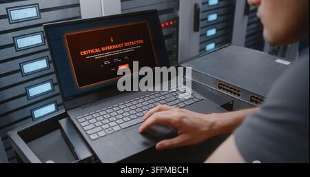 Male Network Engineer Handles Critical Overheating Event Through CLI, Reviewing Server Telemetry and Entering Recovery Commands While Monitoring Moder Stock Photo