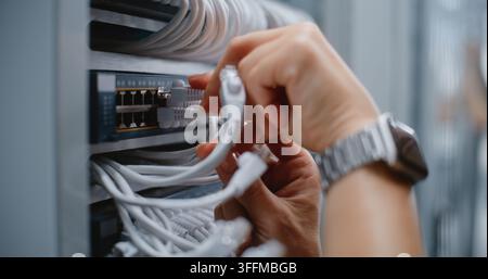 Close Up of Engineer Inspects Server Rack Cabling and Adjusts Ethernet Connections, Using Cable Management to Maintain Clean Routing, Proper Bend Radi Stock Photo