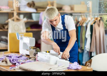 Repairman repairing sewing machine in workshop Stock Photo