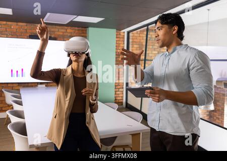 Diverse coworkers using VR headset and tablet at long white meeting table in conference room Stock Photo