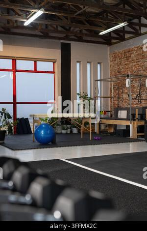 Blue stability ball is resting in front of wooden therapy table on rubber mats, near windows Stock Photo