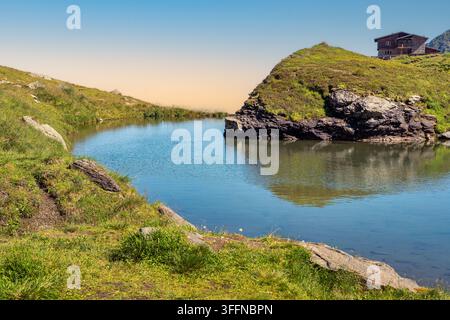 Small alpine lake and remote hut in the Carpathian Mountains of Romania under a clear summer sky Stock Photo