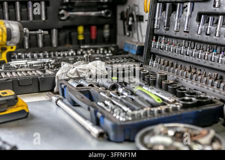 Portable multi-piece mechanic’s socket and bit set open on a workshop bench in a small car repair garage. The organised tool case Stock Photo