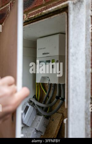 Person checking the electricity meter at a residential property in the UK, inspecting the meter display and household electricity usage Stock Photo