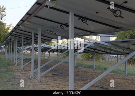 Ground mounted solar panel array showcasing the metal framework, electrical wiring, and the back side of photovoltaic modules generating renewable ene Stock Photo