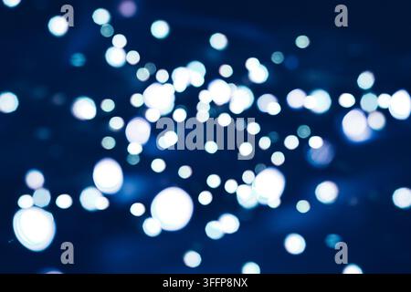 Abstract blue and white bokeh lights shimmering on a dark background creating a magical winter mood Stock Photo