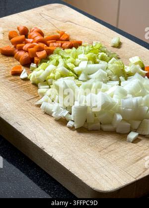 chopped carrots, celery and onions on wood cutting board Stock Photo
