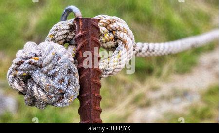 Weathered old cord with a large knot on a rusty iron rod, natural green background, Switzerland Stock Photo