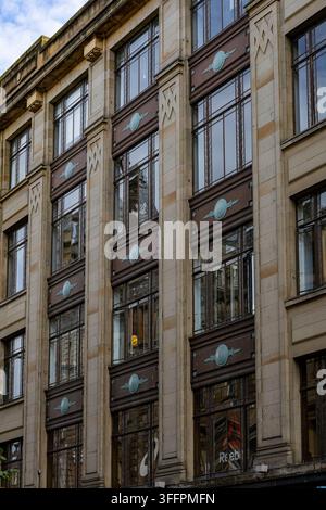 A detailed view of a multi-story building with Art Deco architectural elements, featuring decorative window frames and geometric patterns in Glasgow, Stock Photo