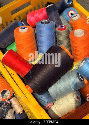 Colorful spools of sewing thread piled in plastic baskets at a market stall in Sousse, Tunisia, a vivid detail of tailoring supplies Stock Photo