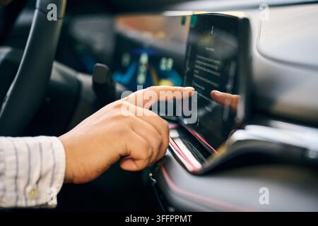 Close-up of a driver using a touchscreen infotainment system inside a modern car, highlighting connected vehicle technology, digital dashboard control Stock Photo